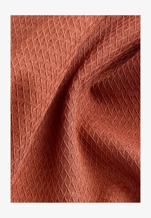 Texturovaná tkanina v hrdzavej farbe s geometrickým vzorom, so soft, tkaným vzhľadom a jemným leskom. Ideálna na čalúnenie alebo oblečenie.