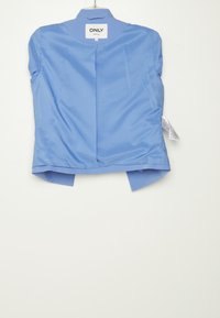 Světle modrá blůza s krátkým rukávem a hladkým lesklým povrchem, se zaobleným lemem a malým límečkem. Značka viditelná na zadní straně.