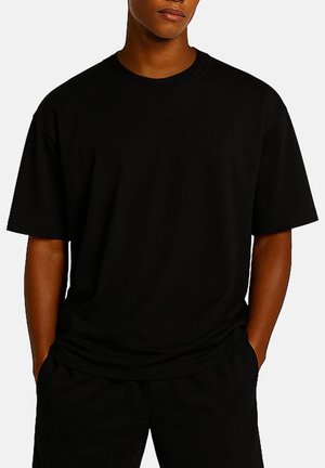 T-shirt in cotone nero con vestibilità rilassata, maniche corte e scollatura rotonda, caratterizzato da una texture liscia e senza motivi visibili.