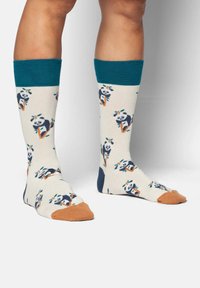 Medias hasta la rodilla en color crema con patrón de pandas y bambú. Puños acanalados en tono teal y acentos en la punta en color naranja. Tela suave con diseño estampado.