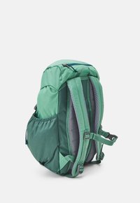 Green backpack with a textured finish, featuring padded mesh back straps, adjustable buckles, and a side pocket for carrying items.
