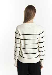 Maglione bianco con strisce orizzontali nere, polsini e orlo a coste; texture liscia con scollatura a girocollo. Senza loghi visibili.