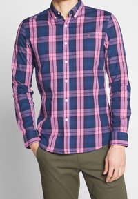 Rutigt skjorta med lila, rosa och blå mönster, knapp-down krage, långa ärmar och liten logotypdetalj på bröstet. Bomullstyg.
