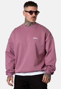 Purple sweatshirt with a crew neckline and long sleeves, featuring embroidered logo on the chest. Crafted from cotton blend material.