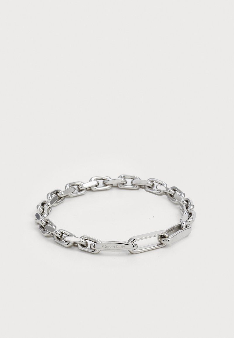 Ezüst lánc karkötő, ovális és téglalap alakú, sima felületű szemekkel. A lapos linken gravírozott Calvin Klein logó.