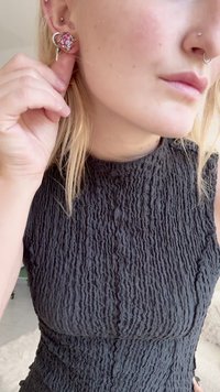 Hõbedast kõrvarõngad ruudukujulise roosa sädelevate mustriga, mille pinnal on tekstuur ja millel on ainulaadne konksuga kinnitustüüp, kantud musta topiga inimese poolt.