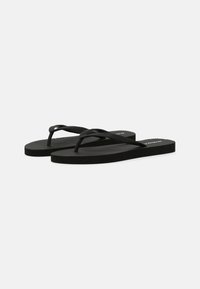 Zwarte flip-flops met een textuur op de rubberen zolen en dunne banden. Het ontwerp heeft een ribbelige oppervlakte voor grip. Eenvoudige en lichte constructie.