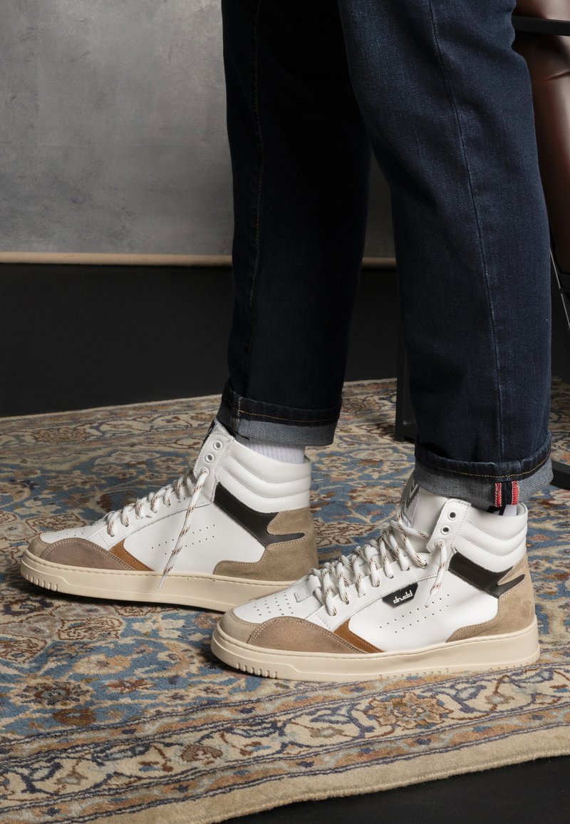 Białe skórzane sneakersy typu high-top z akcentami z tanowego zamszu, teksturowanymi czarnymi syntetycznymi detalami oraz perforacjami na nosku.