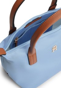 Μπλε τσάντα χειρός από νάιλον με χειρολαβές και φερμουάρ σε ταμπά δέρμα. Διαθέτει χρυσές μεταλλικές λεπτομέρειες και ευρύχωρο εσωτερικό με χωρίσματα τσεπών.