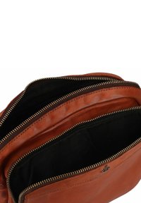 Borsa in pelle marrone con più scomparti con cerniera, caratterizzata da una texture morbida e hardware delle cerniere in tonalità oro. Fodera in tessuto nero all'interno.