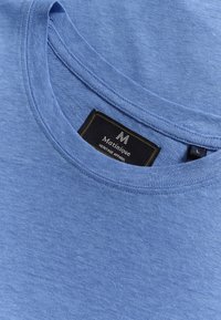 Ljusblå bomulls t-shirt med rund halsringning, mjuk textur och en etikett som säger "Matinique Heritage Apparel" i en kontrasterande svart font.