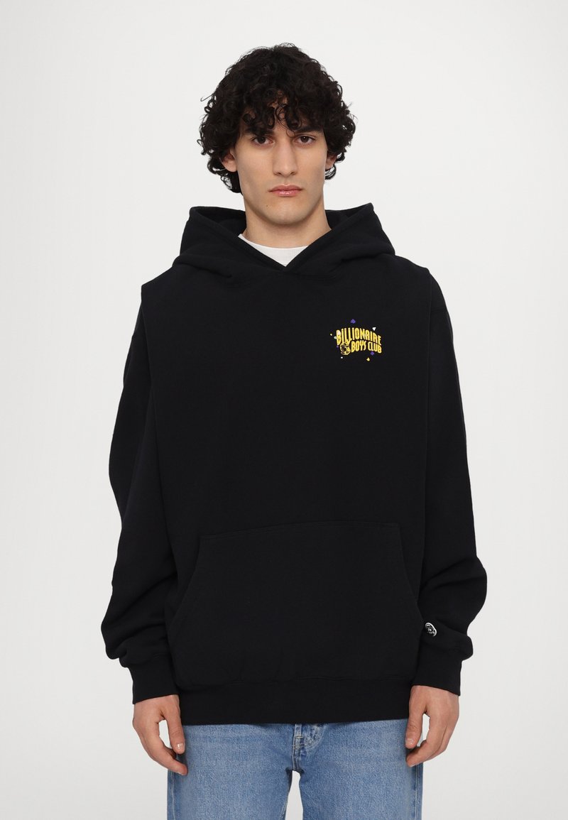 Hoodie noir en tissu doux avec une poche frontale, capuche à cordon de serrage et motif graphique doré sur la poitrine gauche. Coupe standard.
