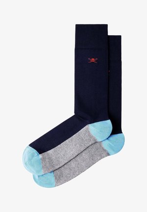 Par de calcetines de longitud media con parte superior azul marino, suelas grises, y dedos y talones azul claro, con un pequeño logo rojo de palas cruzadas.
