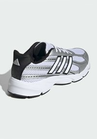 Atletická obuv z bielej sieťoviny s čiernymi akcentmi, striebornými detailmi a podrážkou Cloudfoam. Má tri čierne pruhy po boku.