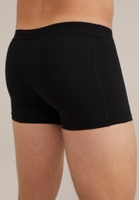 Pantaloni corti trunk in cotone nero elasticizzato con vita liscia, design aderente e cuciture piatte per il massimo comfort. Finitura testurizzata sul tessuto.