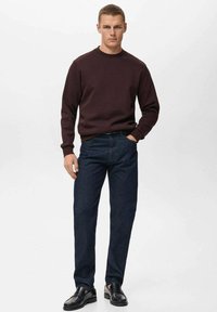 Bordo pulover s kratkimi rokavi, temno modri kavbojki in črnimi čevlji. Pulover ima gladko teksturo; kavbojke so ravno krojene. Preprost, sproščen videz.