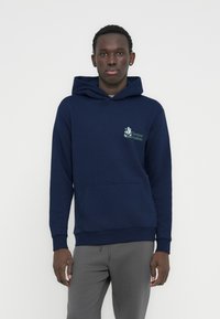 Μπλε σκούρα φούτερ με κουκούλα από μαλακό ύφασμα, με μπροστινή τσέπη και σχεδιασμό γραφικών στο αριστερό στήθος. Μανσέτες και τελείωμα με ριμπ ύφανση.