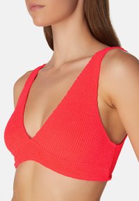 Heller pinker strukturierter Bikini-Oberteil mit dreieckigen Cups und breiten Trägern, das ein geripptes Muster und einen tiefen Ausschnitt aufweist.
