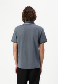 Grå polo t-shirt med korte ærmer, der har en sort krave og gule detaljer på kraven og ærmesømmene. Glat, letvægtigt stof.