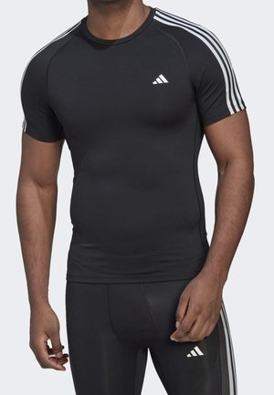 Mann trägt schwarzes eng anliegendes Sportshirt und Leggings mit weißem Adidas-Logo und drei weißen Streifen an Ärmeln und Seiten.