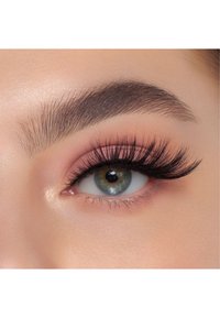 Primo piano di un occhio con lunghe ciglia nere voluminose, un ombretto rosa chiaro e un sopracciglio marrone scuro ben definito. L'iride è verde con un contorno più scuro.