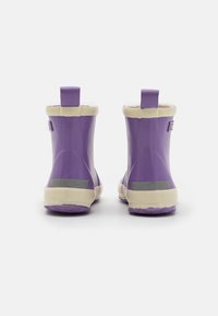 Fioletowe gumowe kalosze z beżowym wykończeniem i podeszwami, pokazane z tyłu, stojące na białej powierzchni.