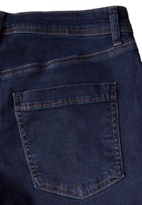 Mörkblå denimjeans med en enda bakficka med spetsig klaff, synlig sömnad i en kontrasterande brun färg. Slät textur.