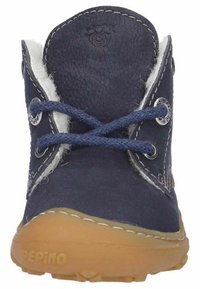 Zapato de cuero azul marino con forro de pelo suave, puntera redonda, dos cordones azules, ojales metálicos y suela de goma marrón con surcos para tracción.