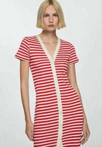 Abito a maglia a righe rosse e bianche con maniche corte, scollatura a V e bottoni chiari decorativi lungo la parte anteriore.