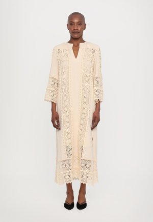 Beige dress with intricate lace detailing, V-neck, three-quarter sleeves, and ankle length. Features lace trim at the hem and sleeves.
