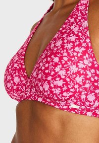 Rosa bikiniöverdel med blommönster, triangel form, mjukt tyg, halterneck-remmar och en slät yta.