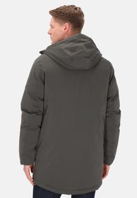 Jachetă izolată gri cu glugă, având o textură netedă, fermoar și detalii de buzunar lateral; purtată de o persoană văzută din spate.