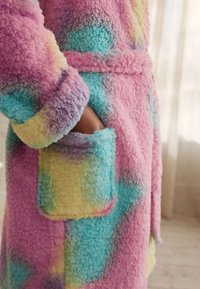 Robe colorée et duveteuse avec un motif géométrique ; présente des teintes pastel rose, bleu et jaune ; comprend une poche et une ceinture assortie.