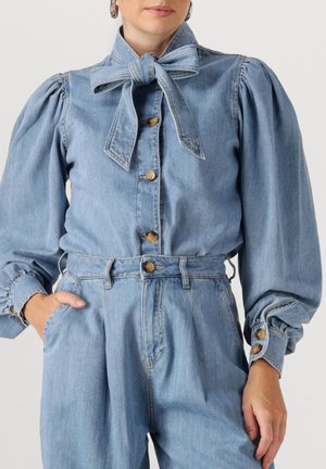 Denim blouse met hoge kraag en strik, pofmouwen en knoopmanchetten, in een lichtblauwe wassing met een sluiting aan de voorkant met knopen.