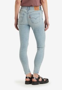 Jeans skinny de un azul claro, confeccionados en denim, con una cintura alta, un ligero desgaste y un parche de cuero en la parte trasera con el logo de la marca.