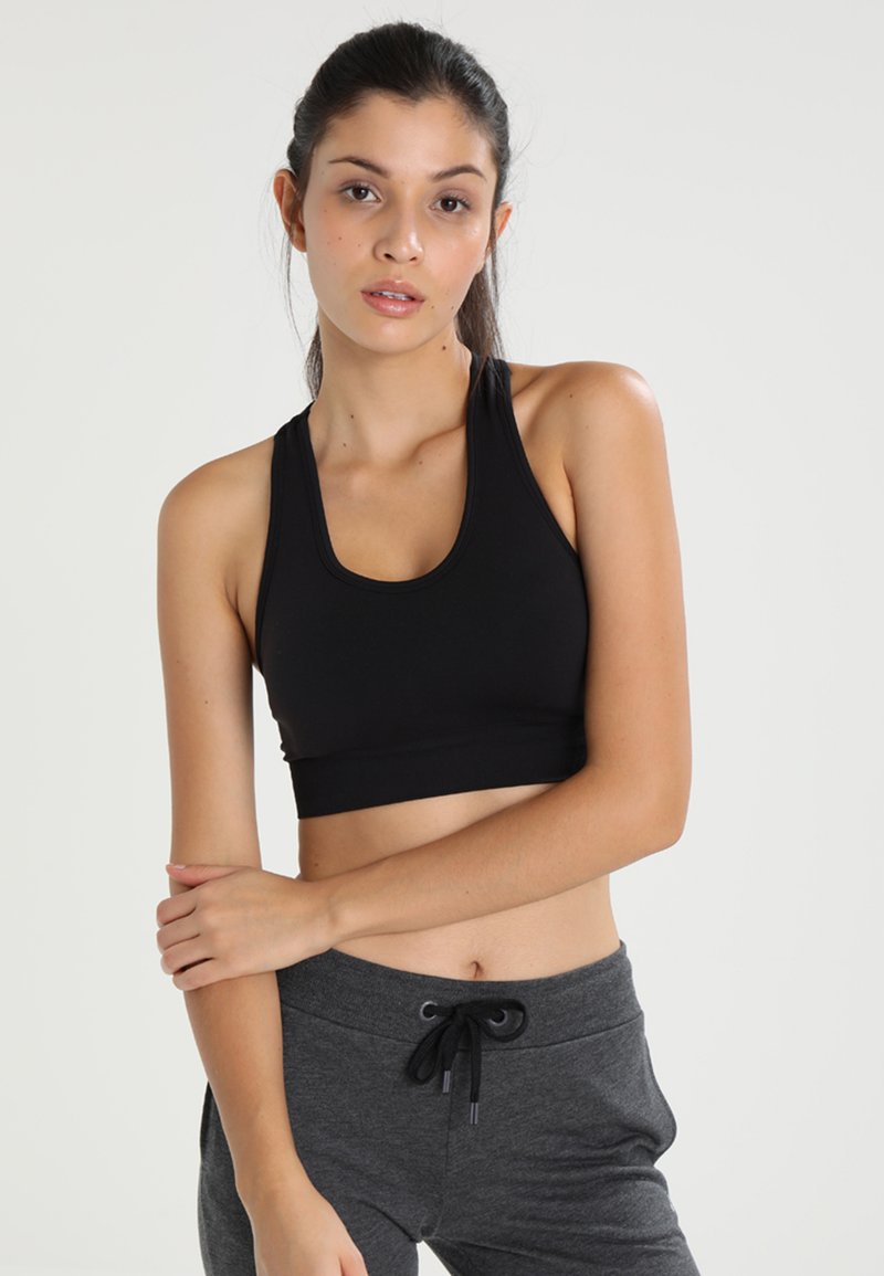 Black sports bra made of stretchy material with a scoop neckline and racerback design, paired with gray elastic waist sweatpants.