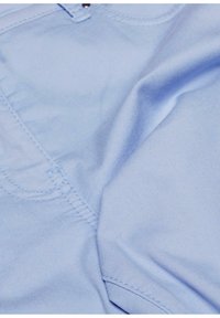 Lichtblauwe stof met een gladde textuur, met zichtbare stikdetails en een lichte draping. Het materiaal lijkt zacht en flexibel.