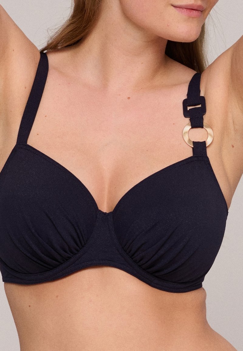 Top bikini blu navy con coppe imbottite, dettaglio arricciato al centro, spalline regolabili e un accento circolare dorato sulla spallina.