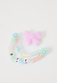 Colorful beaded bracelets with smiley face charms and letters "BFF" beside a pink bow-shaped object on a light background.
