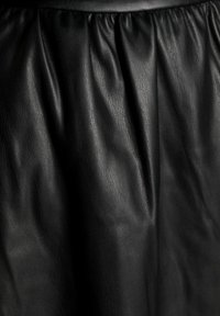 Zwarte leren rok met een gladde textuur, voorzien van geplooide details bij de taille voor volume en vloeiendheid.