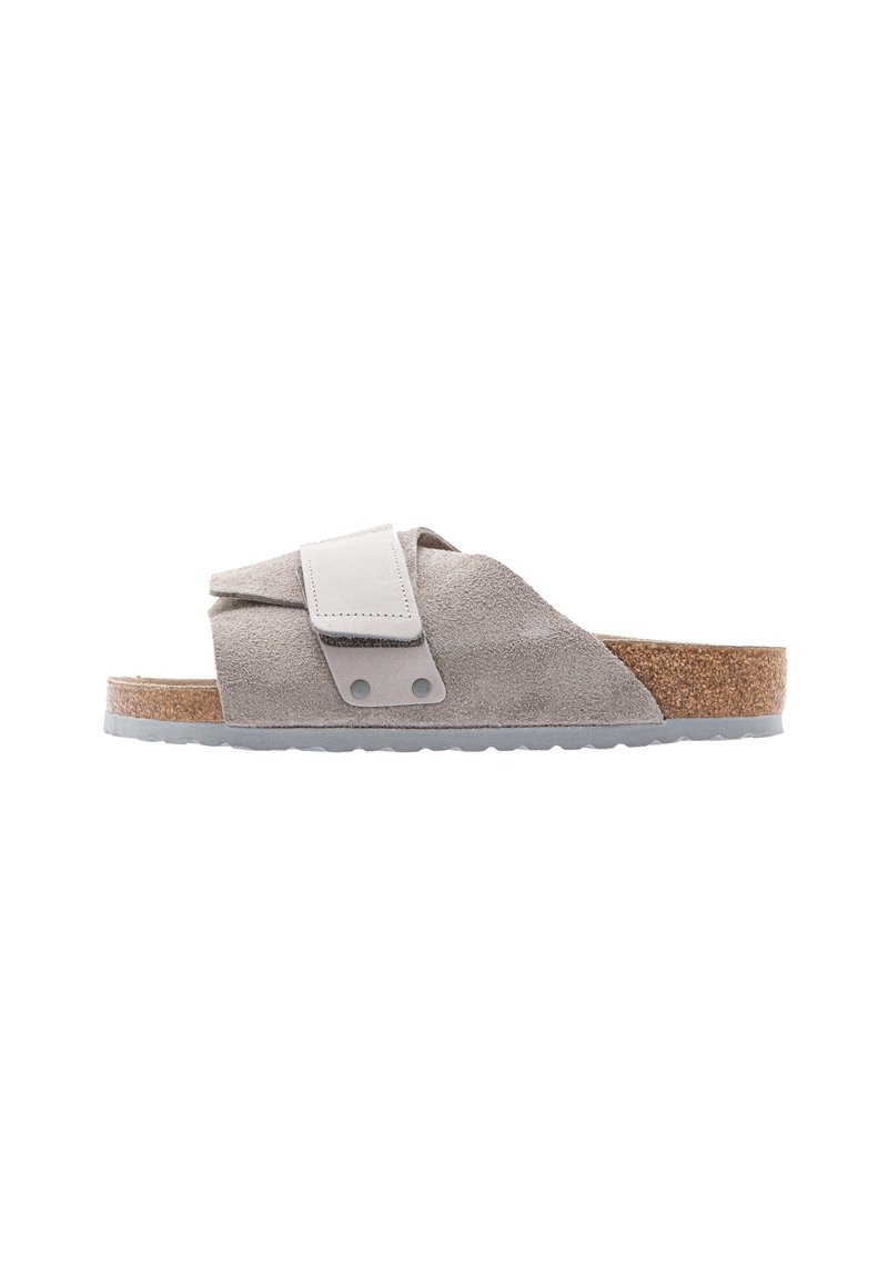 Suede slide sandal in light gray with a cork footbed. Features adjustable strap and gray rubber sole. Sleek, minimal design with soft texture.