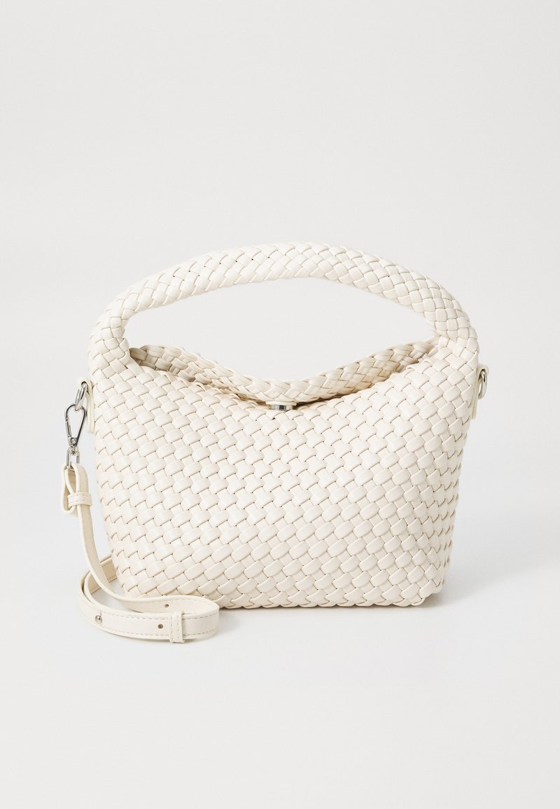 Woven white handbag with a rounded top, a braided handle, and a detachable strap. Soft, textured material with a seamless design.