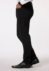 Pantaloni neri realizzati in tessuto liscio, caratterizzati da una linea dritta, tasche laterali e una vestibilità aderente, abbinati a scarpe nere con doppia fibbia.