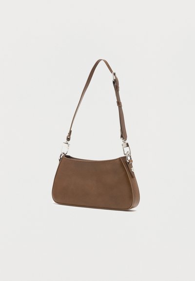 Barna bőr válltáska állítható pánttal és ezüst színű fém kapcsokkal, világos, egyszínű háttér előtt bemutatva.