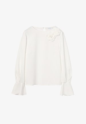 Valkoinen pusero, jossa on pitkät hihat, pyöreä kaula-aukko, liehuvat hihansuut ja kolmiulotteiset kukka-akcentit vasemmalla olkapäällä. Hieno kangastuntuma.