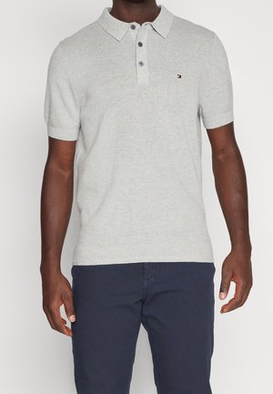 Polo shirt in cotone grigio chiaro con texture a coste, tre bottoni e un piccolo logo sul petto. Maniche corte e un design del colletto classico.