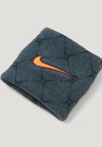 Sportovní náramek Nike ve tmavě modré textilii s texturovaným vzorem. Na přední straně je vyšitý oranžový znak swoosh. Kompaktní obdélníkový tvar.