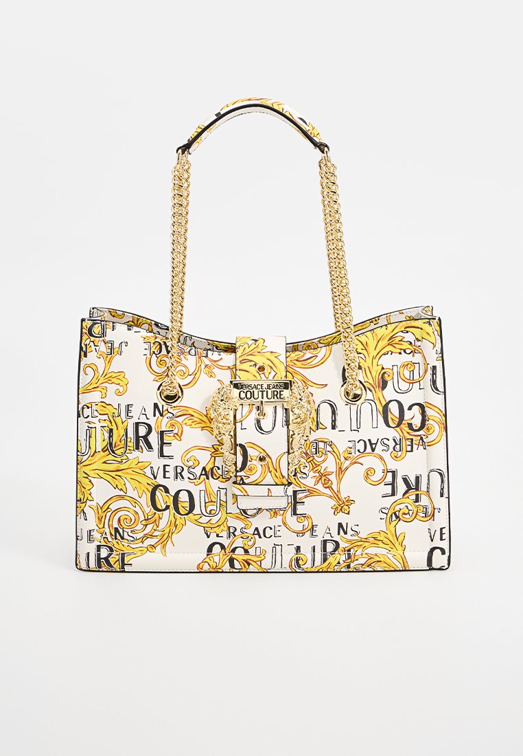 Tasche mit goldenen Kettenhenkeln, weißem Hintergrund, gelbem Blumendesign und schwarzem Text. Verfügt über einen goldfarbenen Verschluss und dekorative Akzente.