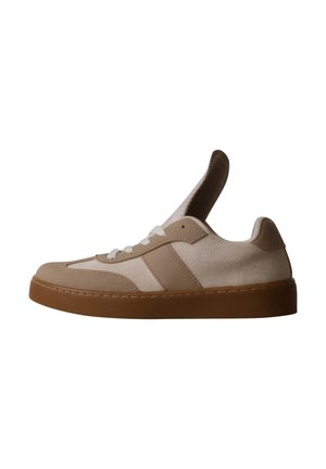 Baskets basses beige et blanches avec semelle en gomme et languette allongée, debout sur un fond blanc.