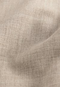 Jasnobeżowa tkanina lniana o gładkiej fakturze, z subtelnym wzorem splotu i miękkim, delikatnym układem draperii.